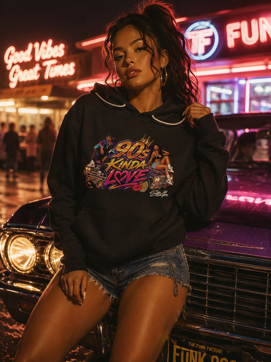 A woman wearing a black graphic hoodie with a colorful retro 90s graphic on the chest, posing in front of a vintage car at night with neon signs in the background.